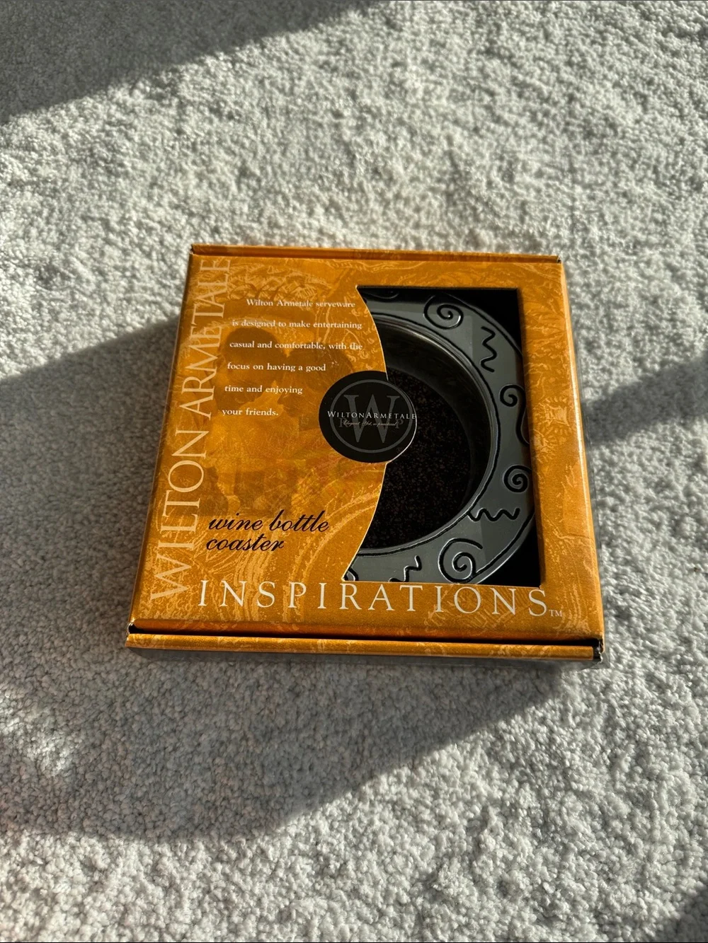 Silver wine bottle coaster with decorative swirl rim.